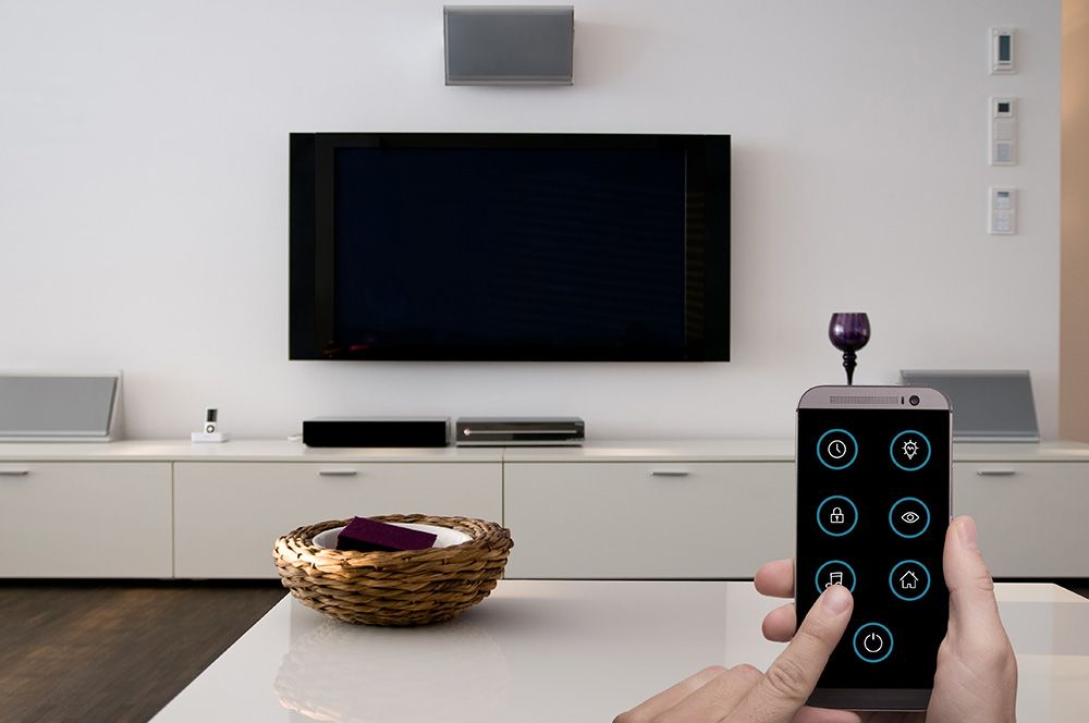 Ein Fernseher und ein Couchtisch und eine Person mit einem Handy, welche eine Smarthomeapp besitzt | Elektro Andreas Merker