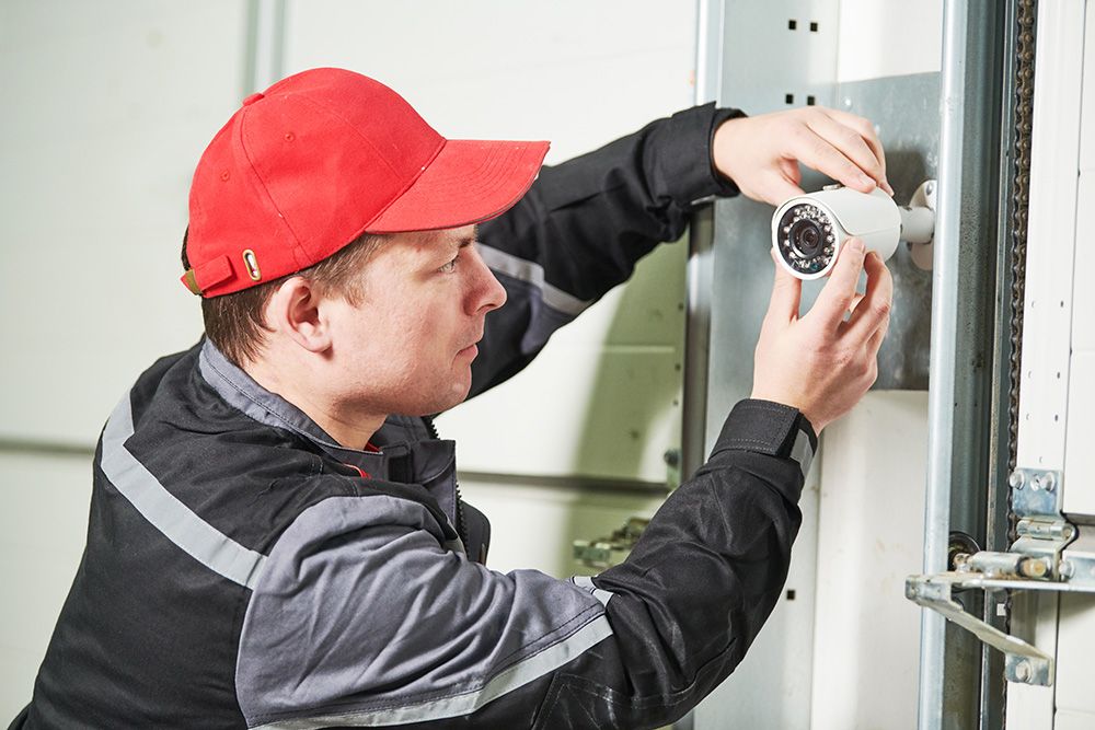 Ein Mann mit rotem Basecap installiert die Videoüberwachung  | Elektro Andreas Merker